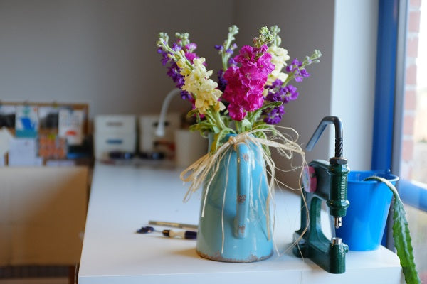 A blue vase of flowers on a workbench