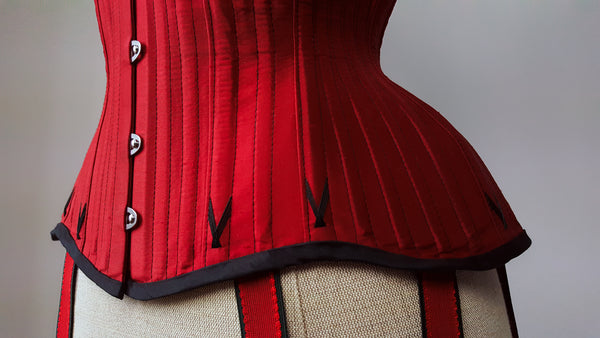 Close up of a red silk corset with black flossing embroidery