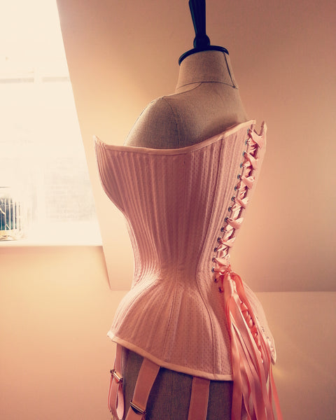 Rear view of extremely curvy pink overbust corset made for a male tightlacer.