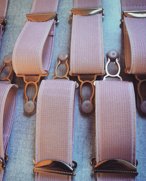 Pink suspender straps with gold fastenings.