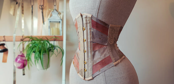 A blush and earthtone silk ribbon corset with gold busk fastening