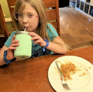 mason jar lifestyle child drinking water from a jar with straw hole lid, straw, and silicone sleeve 