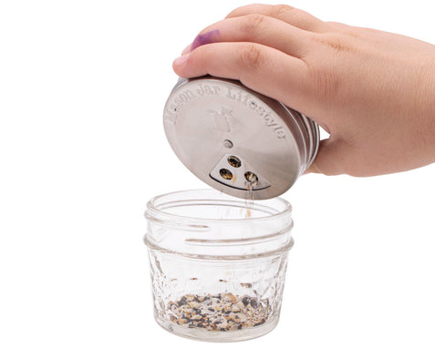 https://cdn.shopify.com/s/files/1/0814/5482/5753/files/mason-jar-lifestyle-regular-mouth-stainless-steel-spice-shaker-lid-large-three-hole-seed-mix-in-use.jpg?v=1695767528&width=477