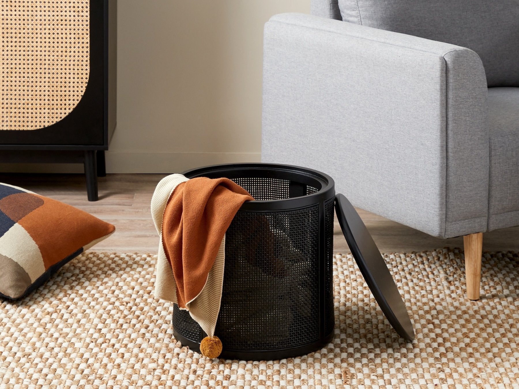 a black rattan ottoman with a removable lid