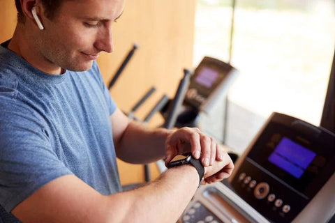 Man wearing a watch while walking on a treadmill exercising