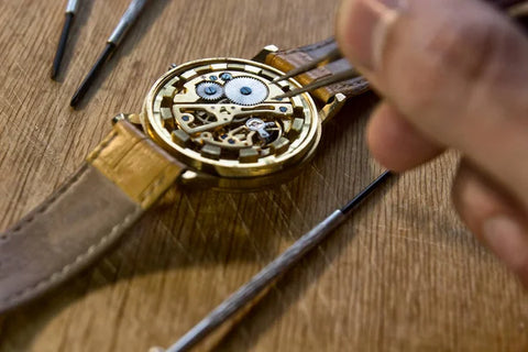 Mechanical watch getting repaired by a watchmaker on top of a table