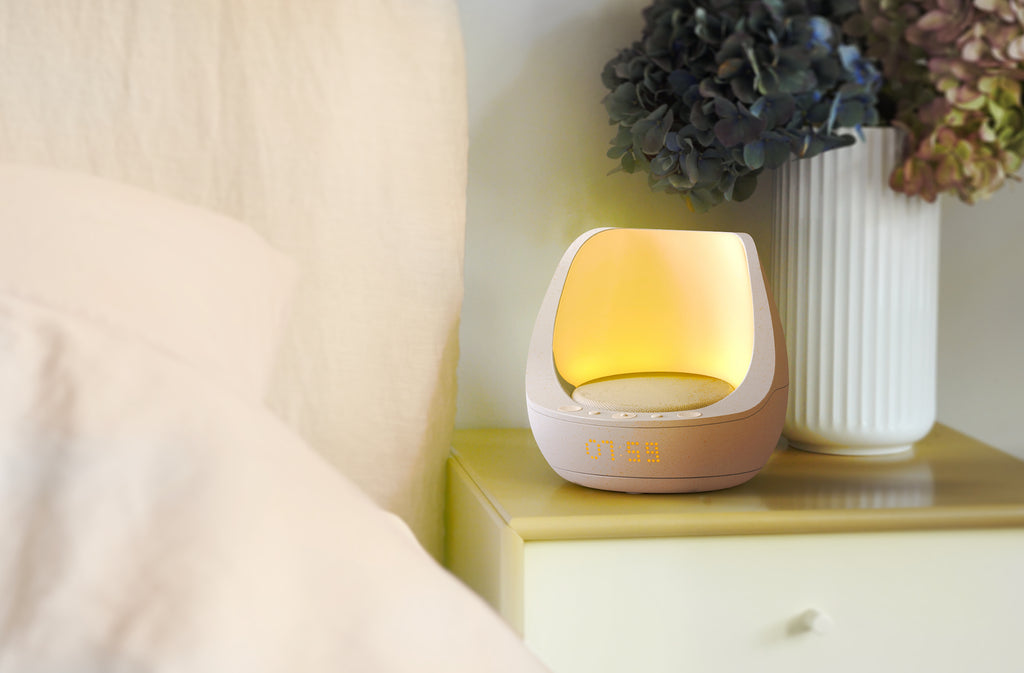 Selah søvnklokke med påskrudd wake-up light (oppvåkningslys) står på et beige nattbord - digitalklokken viser 06:59