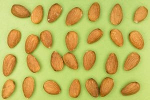 Whole almonds arranged in a column on a green background