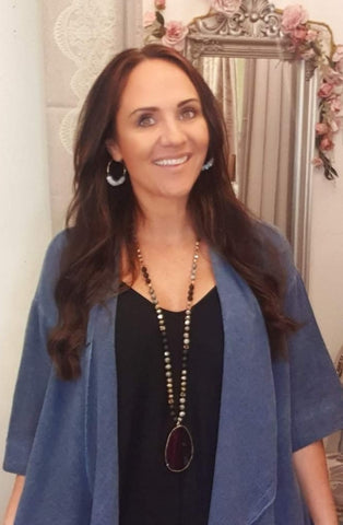 Lynnette in photo wearing navy linen jacket and black jumpsuit with beaded necklace