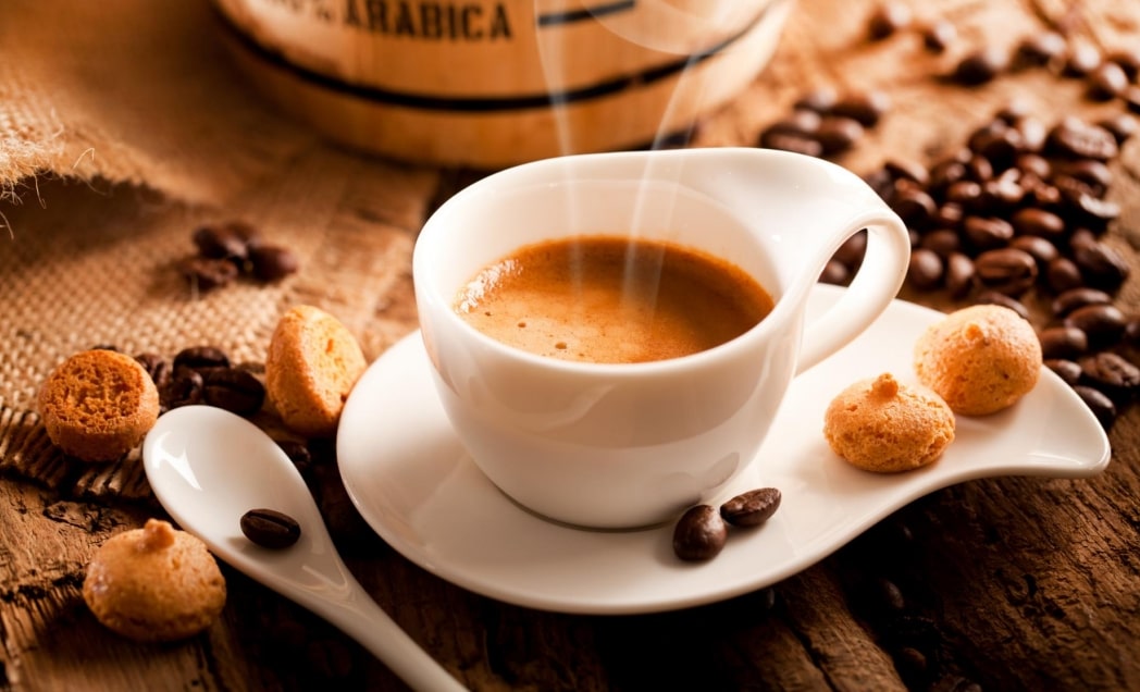 a cup of espresso on the table surrounded by beans and cookies
