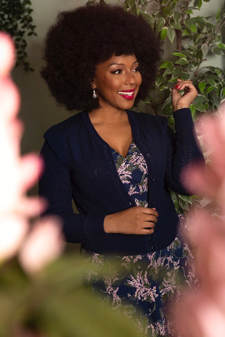 women wears blue cardigan over floral print dress on blue base