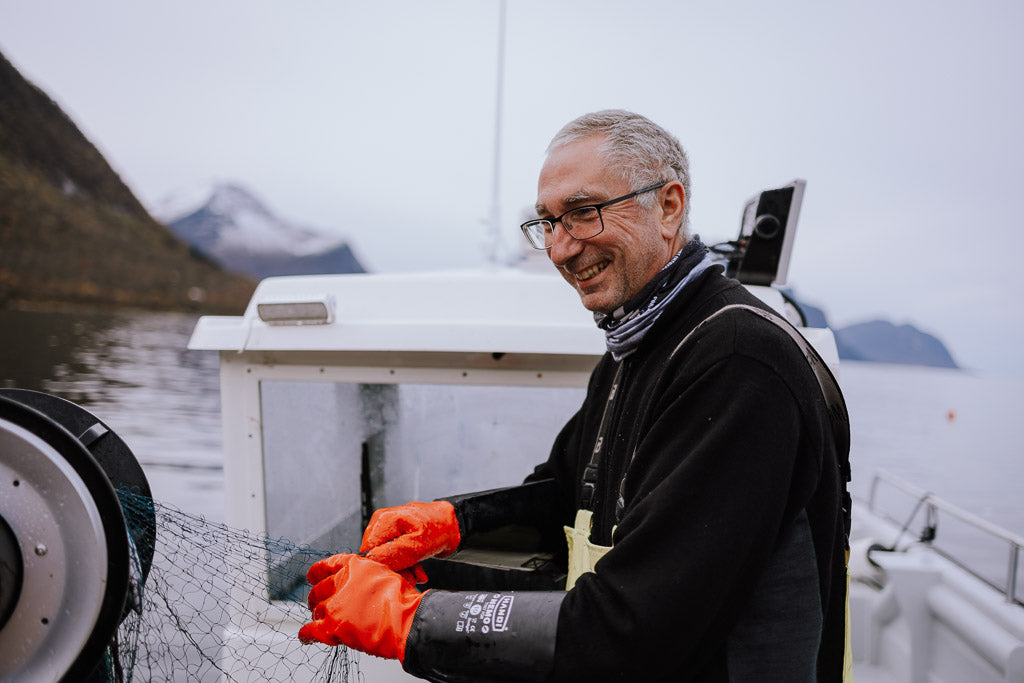 Kjell Ivar som smiler på en fiskebåt. Foto.