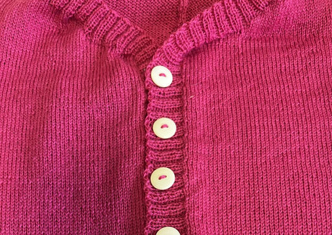Håndstrikkede knappestolper, detaljfoto fra rosa ulldress. Foto Merethe Skille
