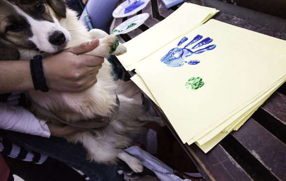 painted dog paw and human hand on paper