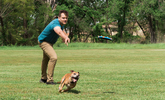 a man throwing a Chuckit! Fetch Toy for a dog to fetch