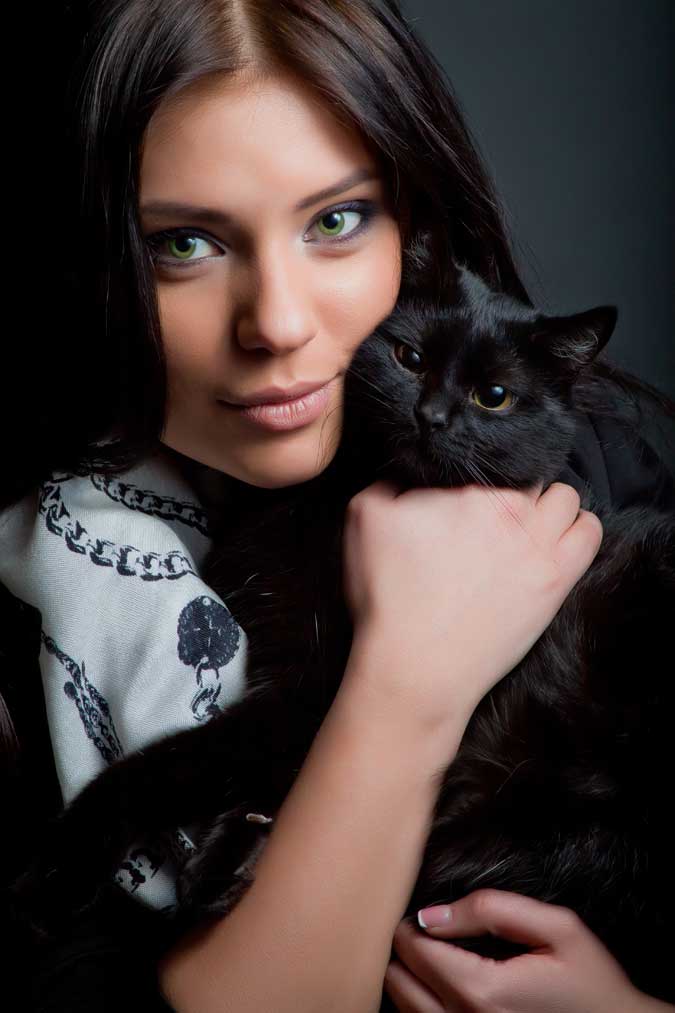 a beautiful woman hugging a black cat