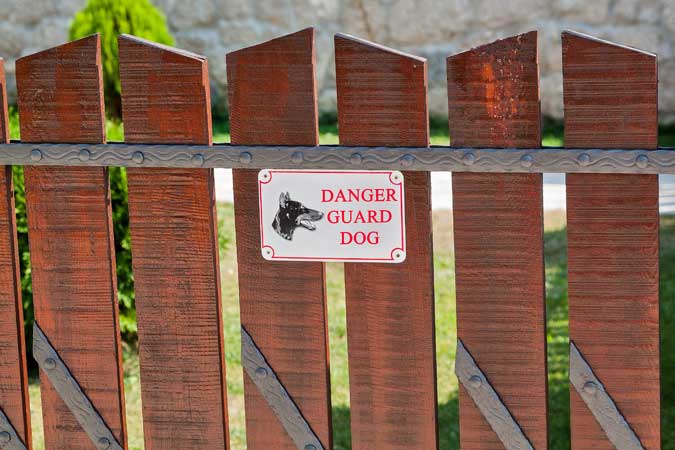 Beware Of Dog sign on a fence in front of a home