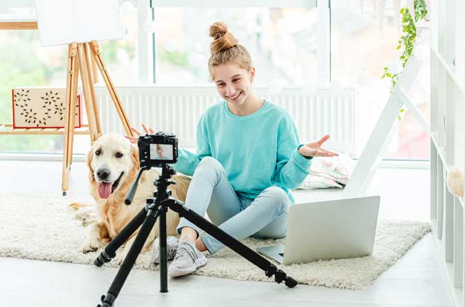 a lady taking a picture with her dog in her living room using a camera on a tripod
