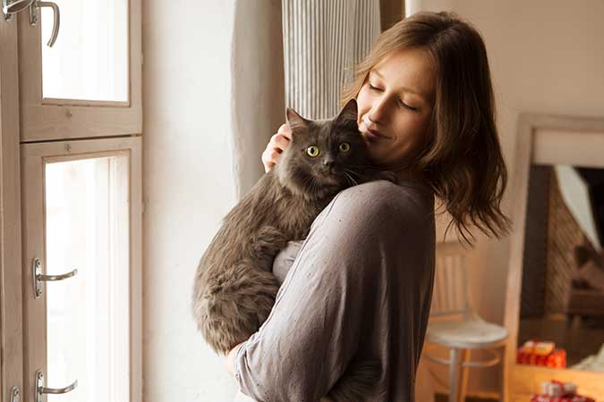 a young woman holding a black cat in her arms