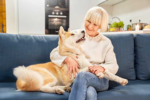 a woman cuddling with her dog on a couch indoors