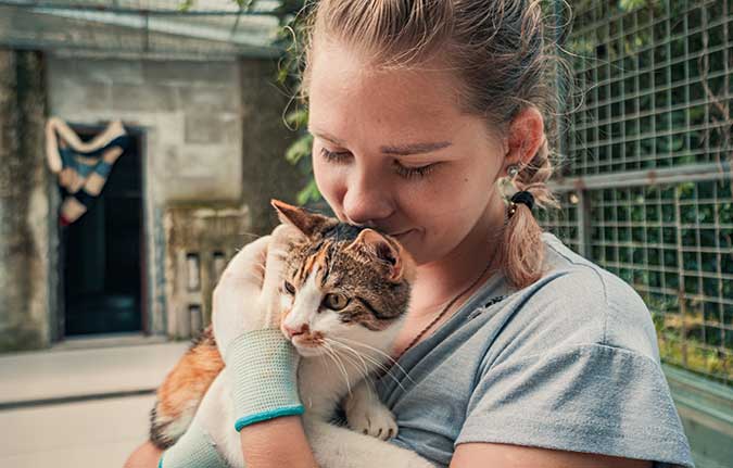 a pet shelter voluteer cuddling with a cat