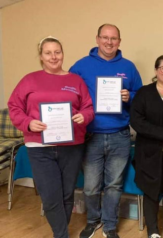 Chris and Caroline holding their dog first aid certificates