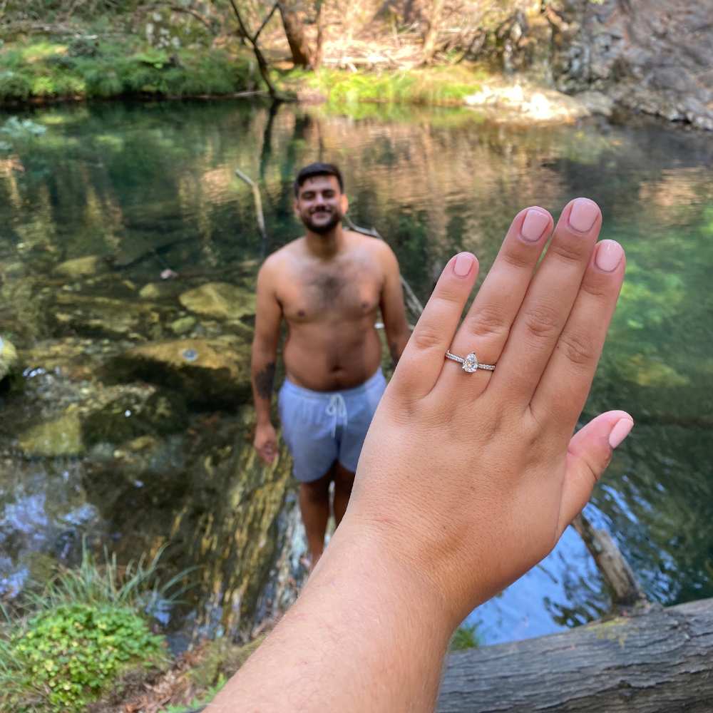 Engagement ring worn on hand worn up against lake.