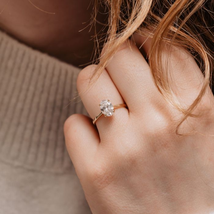 Slim Oval cut solitaire worn on models hand.