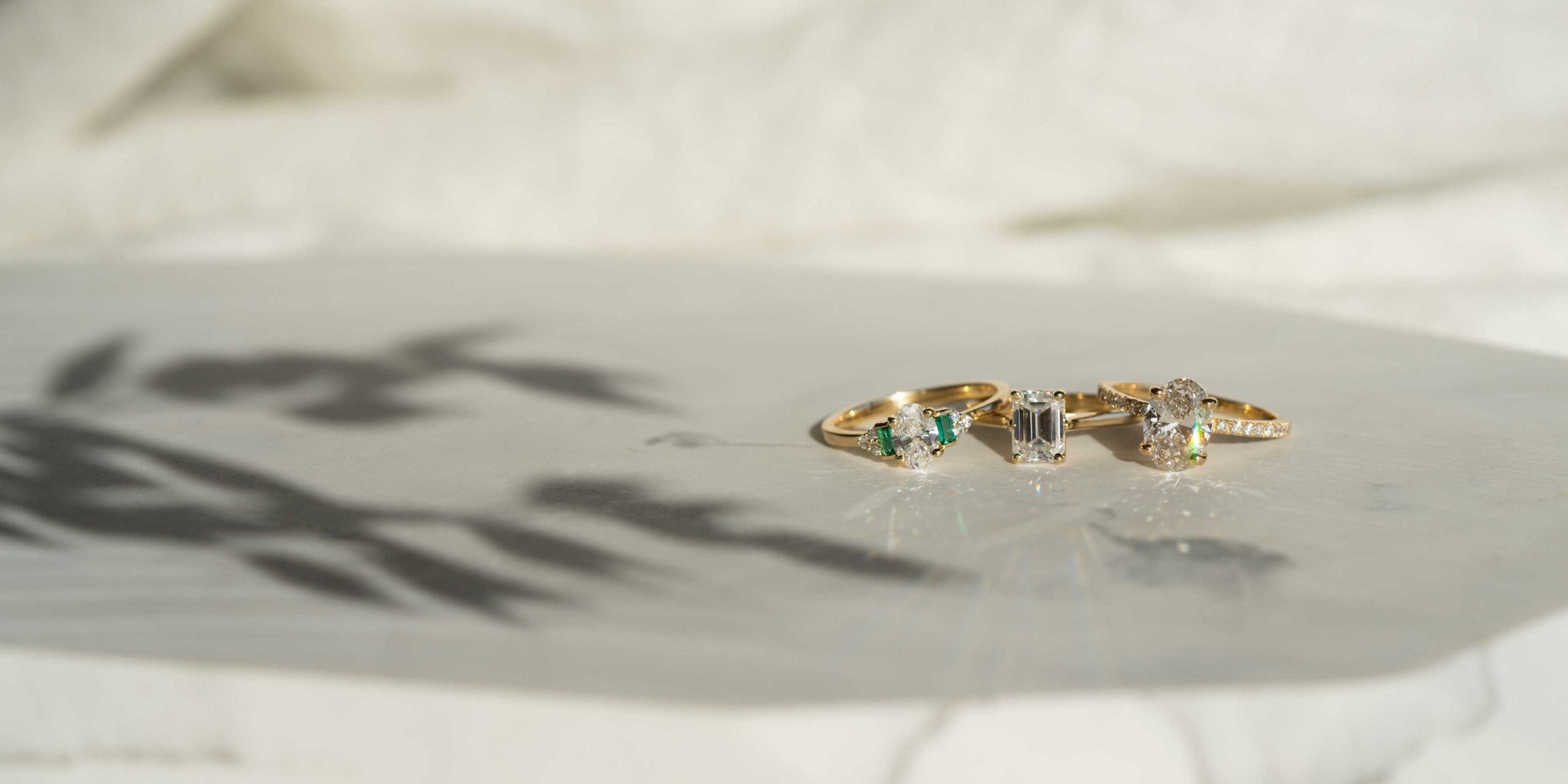 three gold diamond engagement rings resting on marble