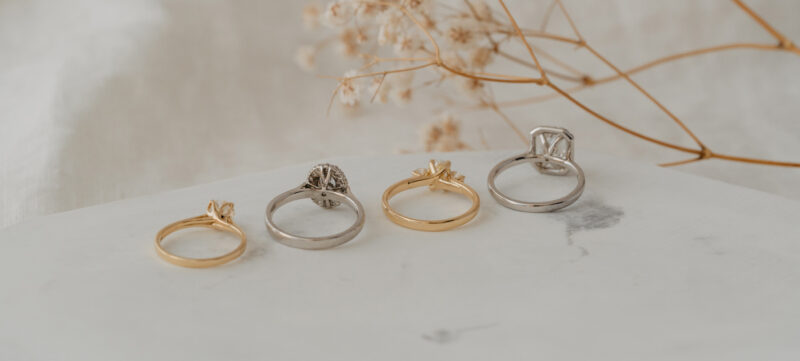 four engagement rings facing backwards in platinum, yellow gold, rose gold and white gold