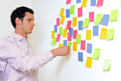 man putting sticky notes on wall