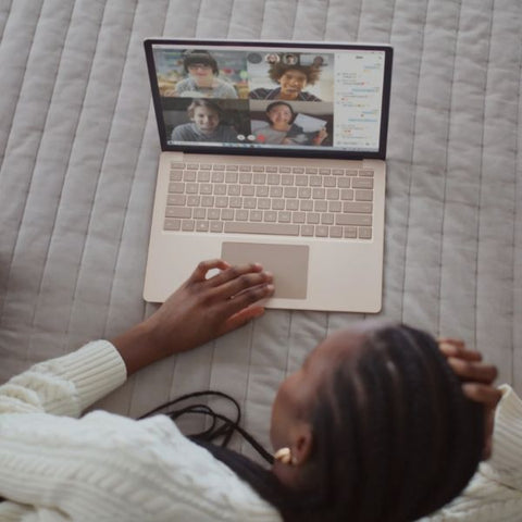 A young women lying on her bed on chatting to her family on a video call