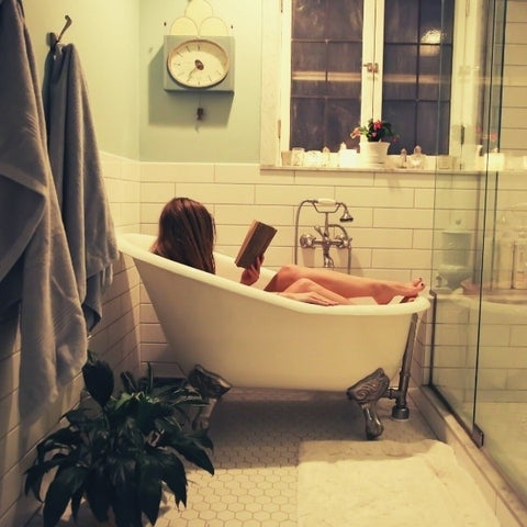 Lady in bath relaxing with book - pamper night in