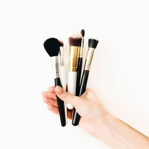 Person holding a handful of make-up brushes