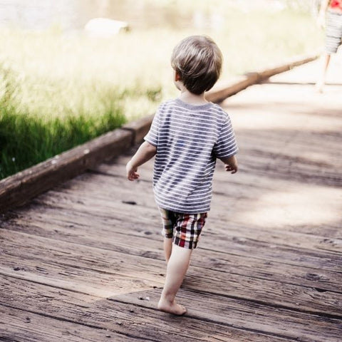 A child walking across a wooden bridge by a lake