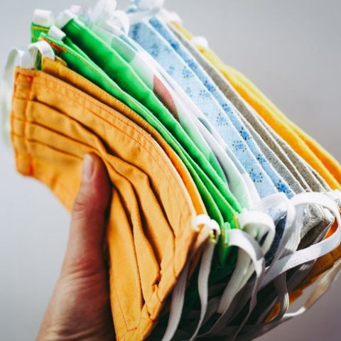 Person holding a bunch of reusable cotton masks 