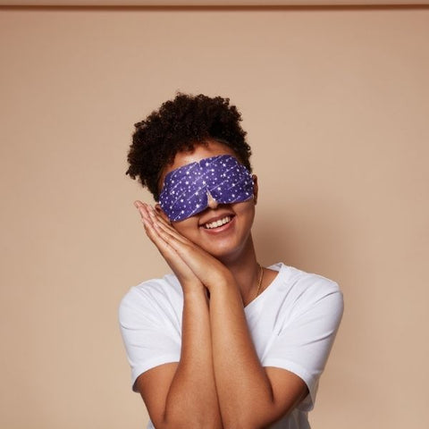 A woman posing as if she is a sleep wearing a spacemask (self heating eye mask) over her eyes