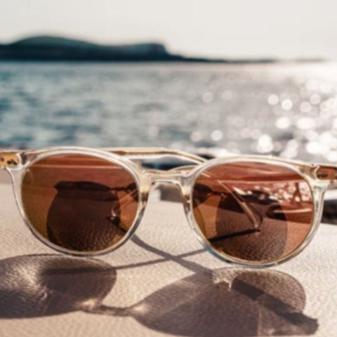 Image showing rose-gold sunglasses resting on a sun bed with the ocean in the background