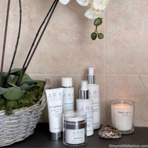 Product Image of a range of ARK Skincare products on a bathroom counter next to an Orchid. 