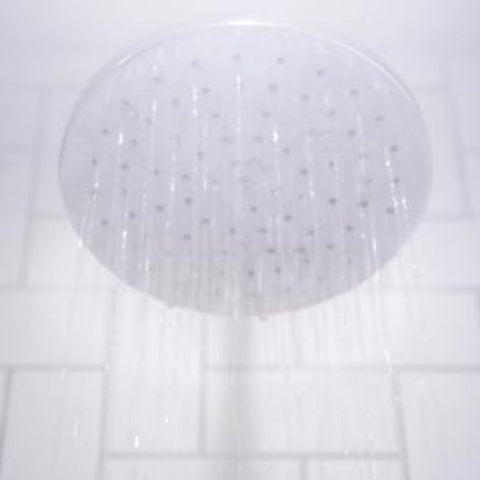 Image: Water streaming from shower head against white bathroom tiles