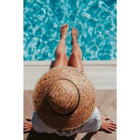 Image: Woman sat on the side of a pool dipping her feet into the water