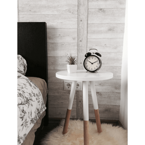 Image of a white wooden bedside table holding an alarm clock and small plant