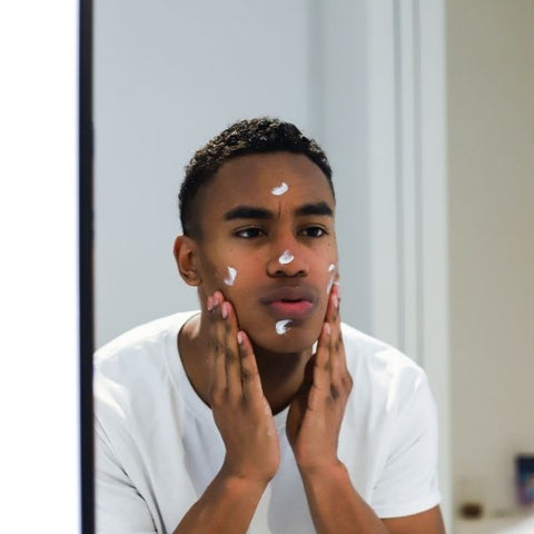 Man applying moisturiser to his face in the mirror