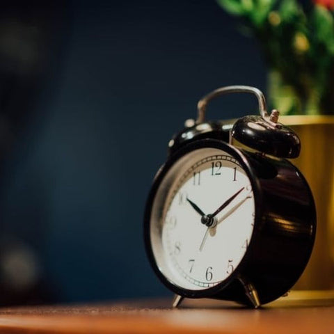 Old fashioned black alarm clock on a wooden counter