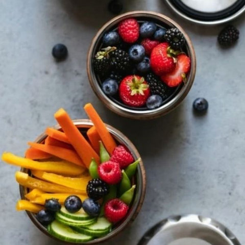 Two bowls of carrot sticks, pepper strips and fresh berries