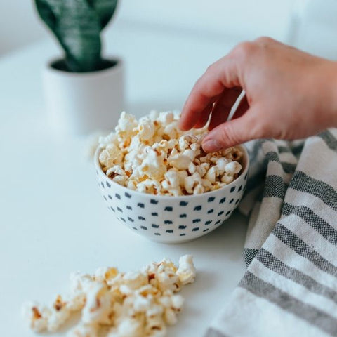 A person helping themselves to a bowl of popcorn