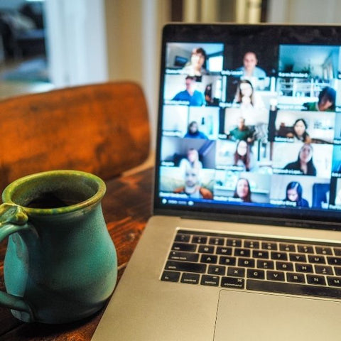 A silver laptop screen with a live zoom event with lots of people chatting to each other