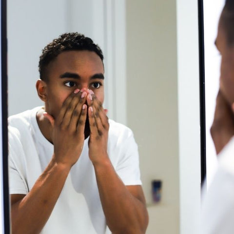 Man washing his face over a sink in a mirror