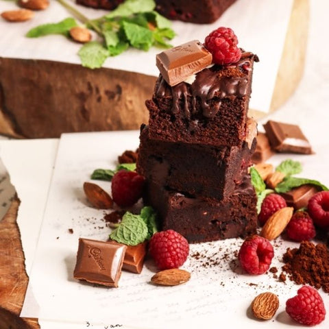 A stack of home-made chocolate brownies with raspberries and chocolate