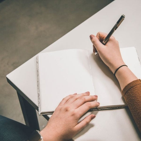 A person writing notes down into a plain journal